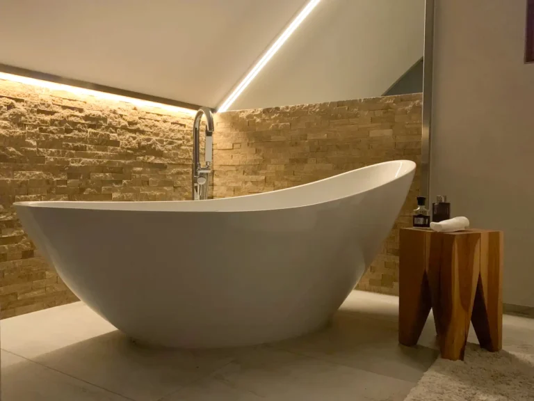 freistehende Badewanne mit Steinwand im Hintergrund